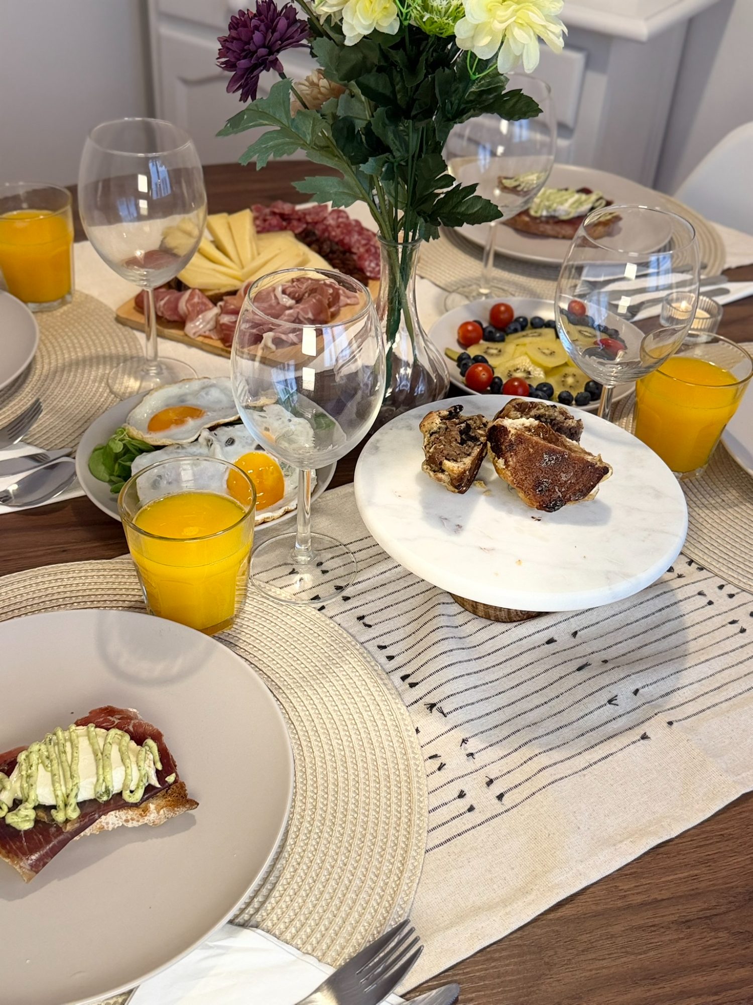 Mesa de brunch puesta con tabla de ibéricos, tostas, fruta y copas